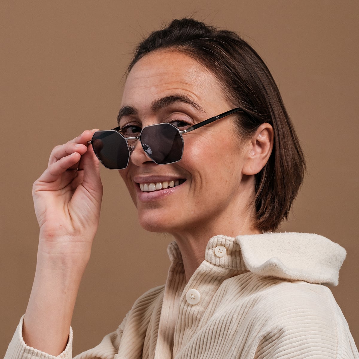 "The Magical" sunglasses, featuring a chic maple and antique silver finish, worn by a smiling woman.