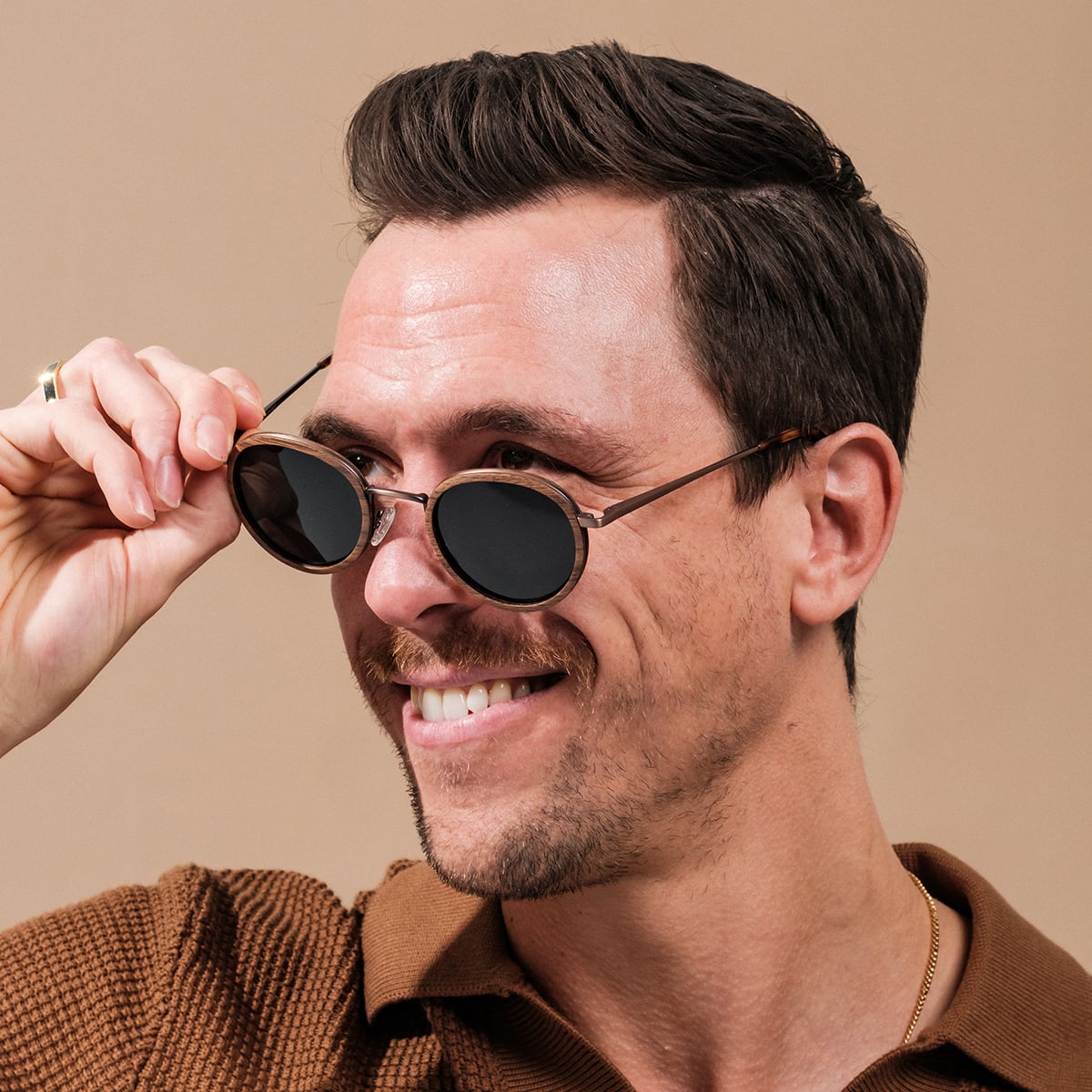 "The Radiant S" sunglasses feature a sleek walnut and copper design with a modern, stylish look.