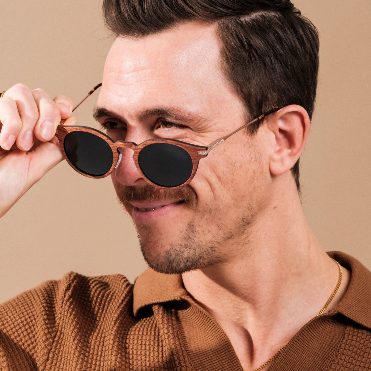 "The Maverick" sunglasses, featuring a stylish padouk wood and copper design, worn with a confident smile.