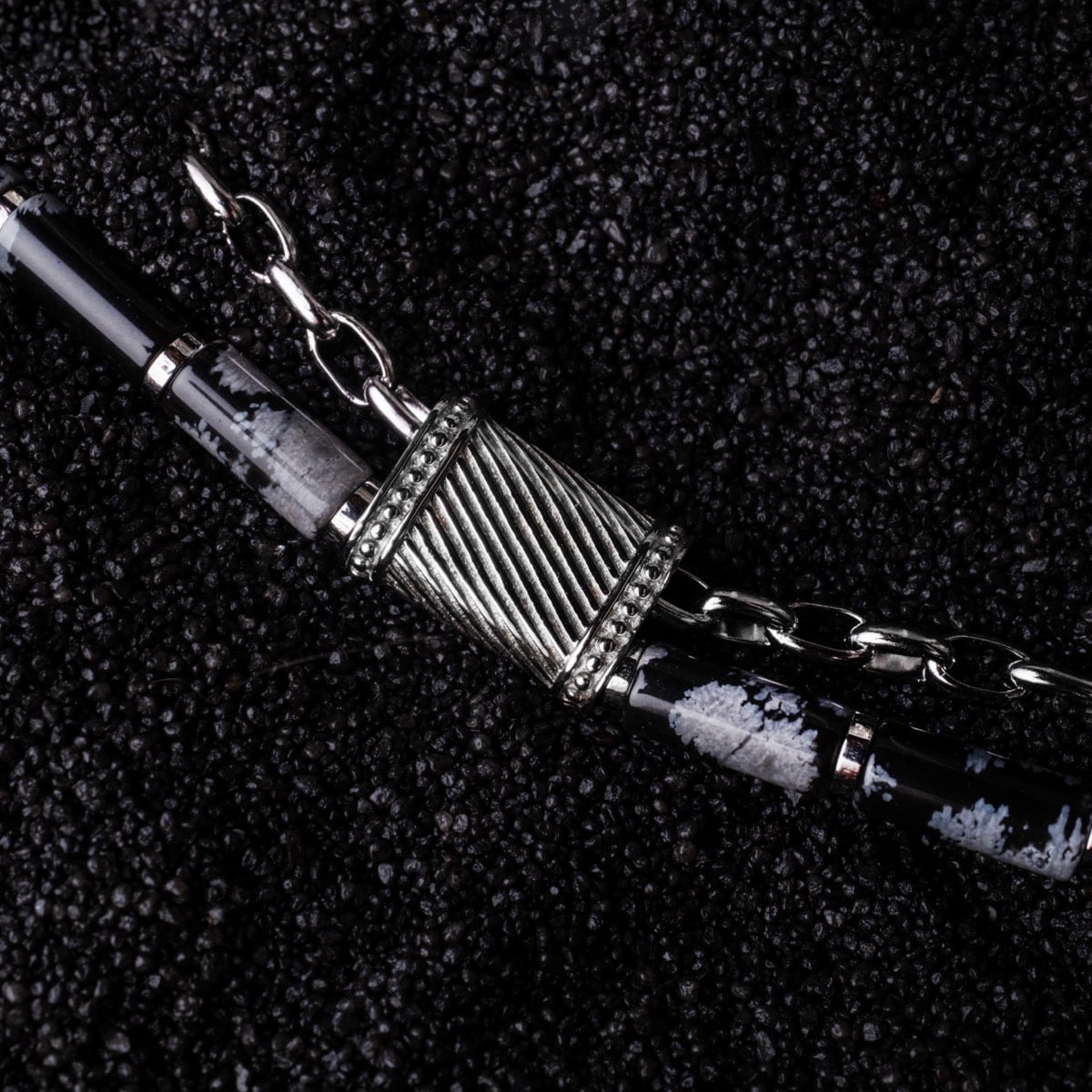 "Supersonic", a sleek chain bracelet in obsidian and silver, showcasing a textured, modern design.
