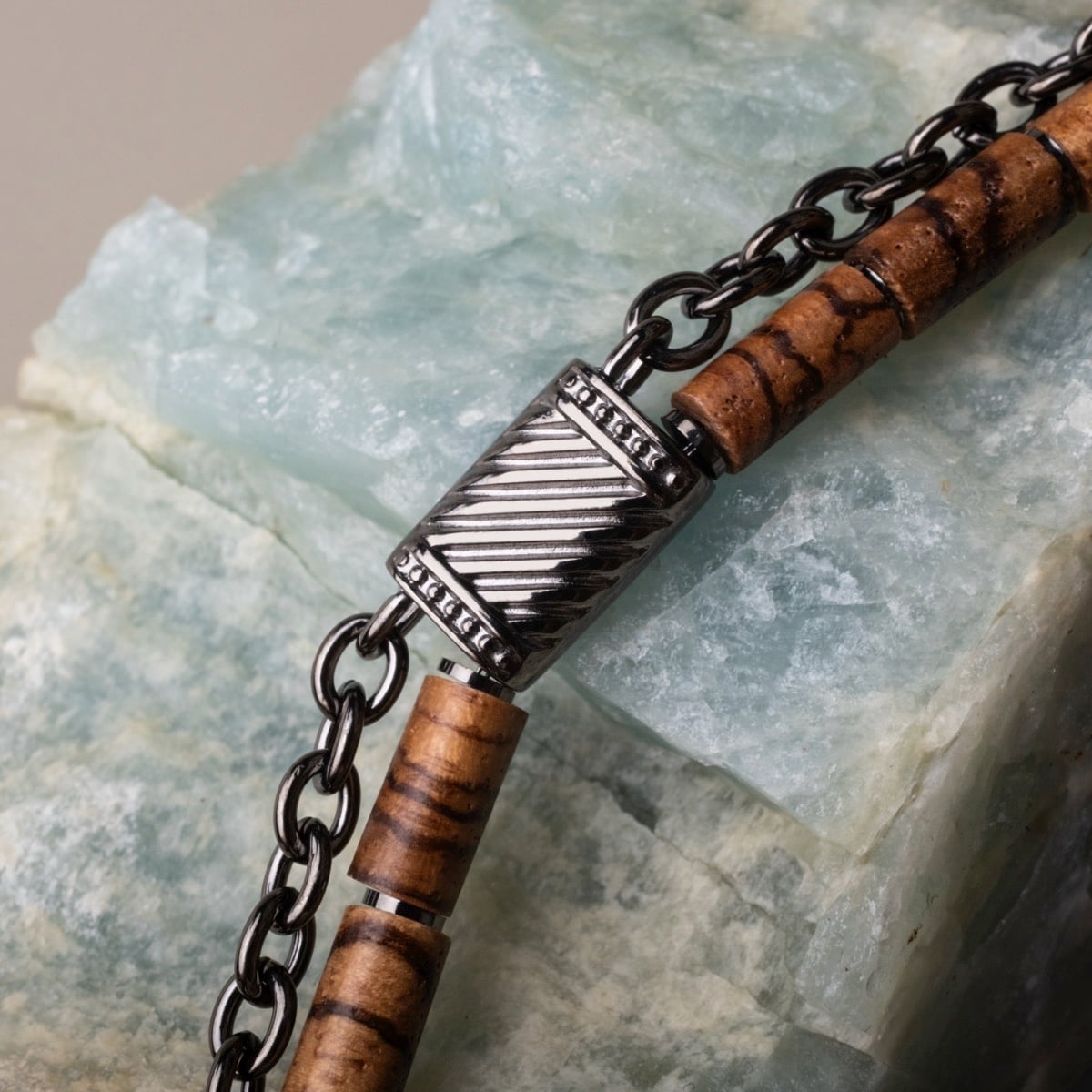 "Supersonic" necklace featuring a zebrawood and gray metal chain design on a stone backdrop.
