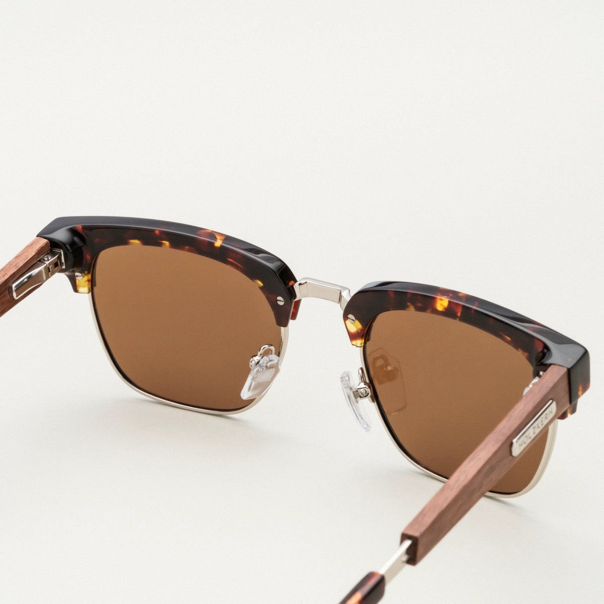 "The Virtuoso" sunglasses, featuring a Walnut/Havana style with elegant, textured brown frames and clear nose pads.