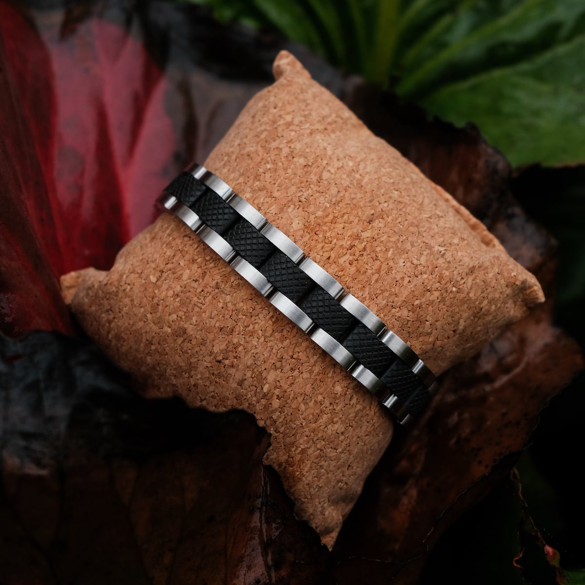 "Accord" bracelet featuring a sleek maple and silver design on a cushion with a natural backdrop.