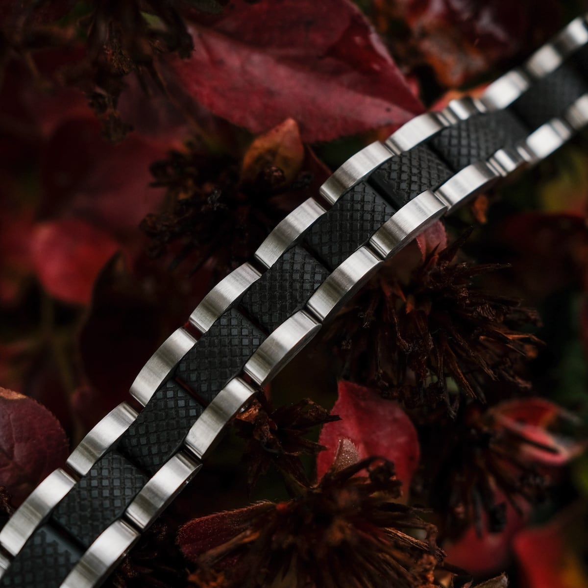 "Accord", stylish bracelet with a textured maple and silver look, set against vibrant red backdrops.