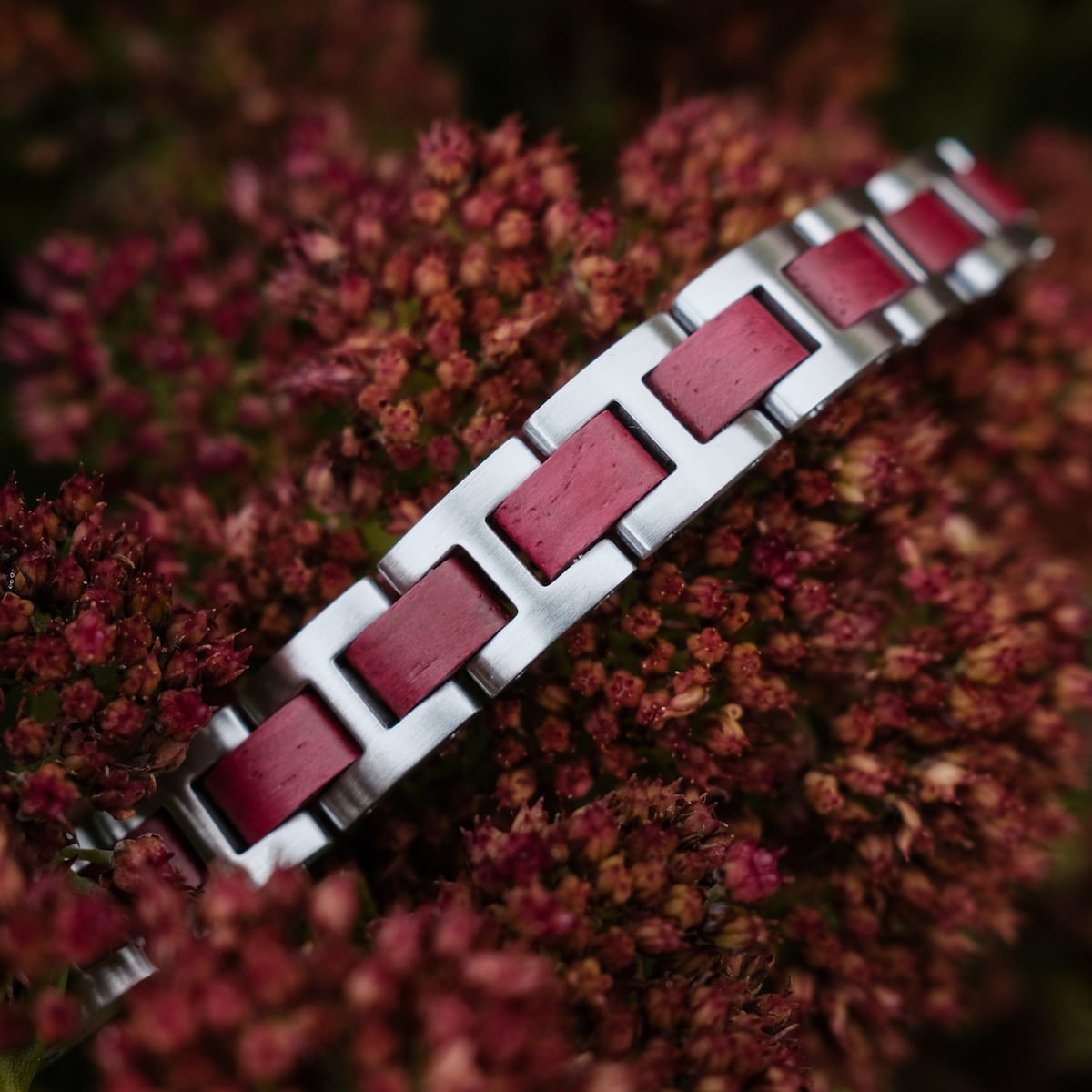 "Acoustic" bracelet featuring amaranth and silver materials, styled against a floral background.