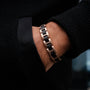 "Acoustic" bracelet featuring a sleek metal link design in maple and rose gold tones, worn on the wrist.