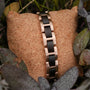 "Acoustic" bracelet featuring a sleek combination of maple wood and rose gold in a natural outdoor setting.