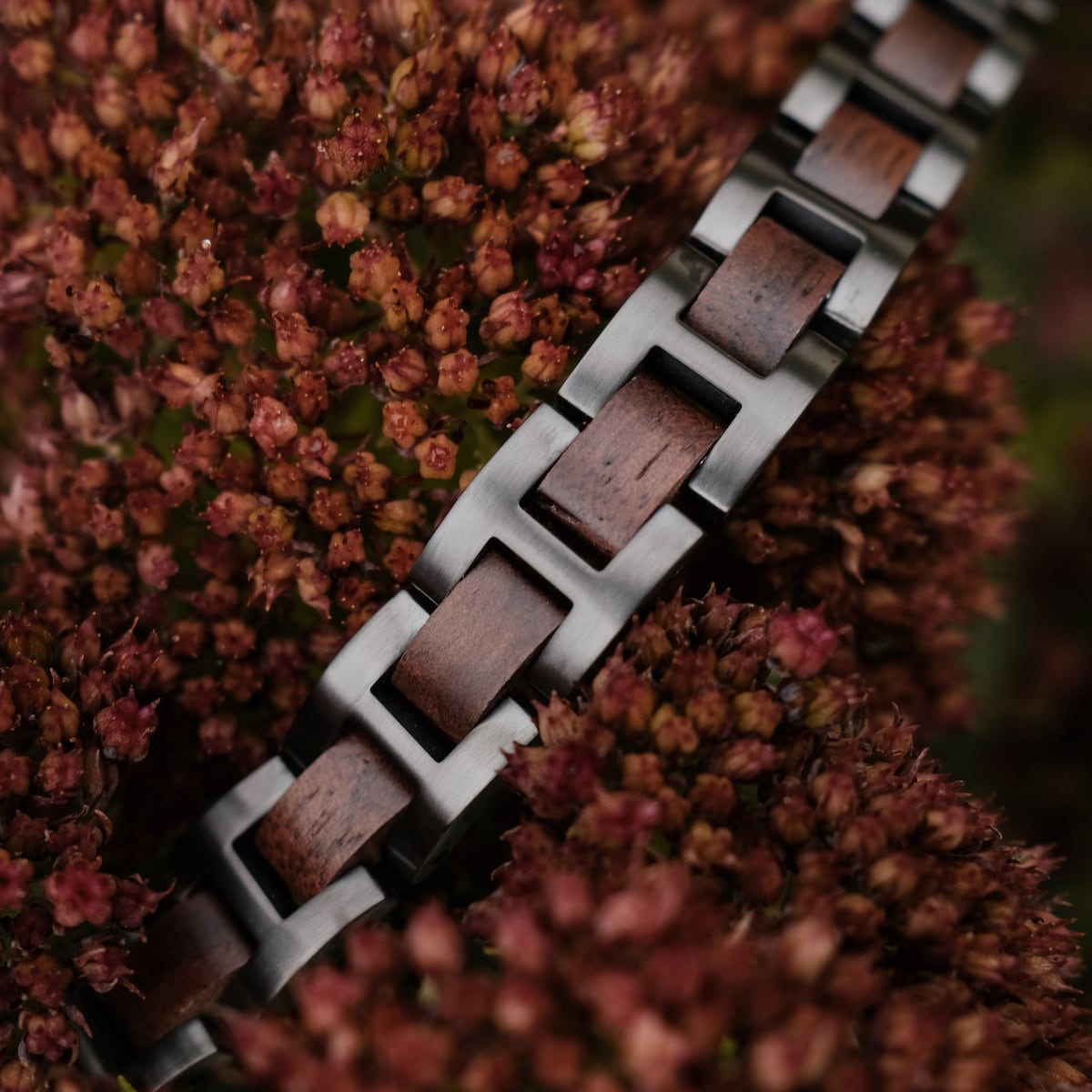 "Acoustic", a stylish bracelet featuring walnut and gray metal links among red flowers.