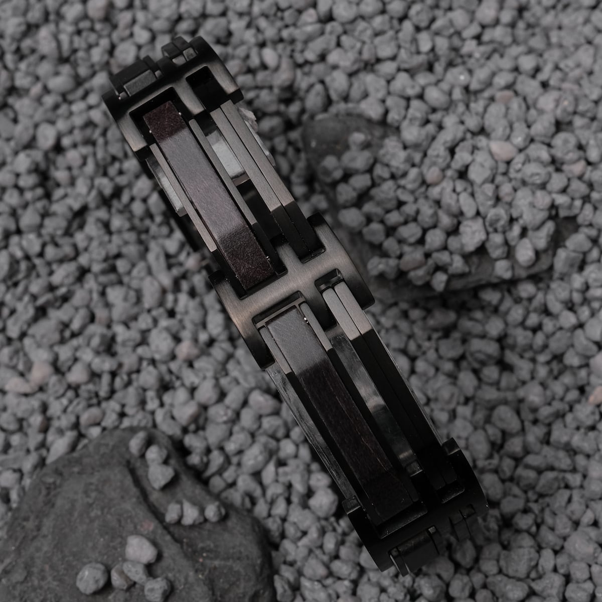 "Staccato", a maple and black bracelet, features a sleek and modern design on a rocky background.
