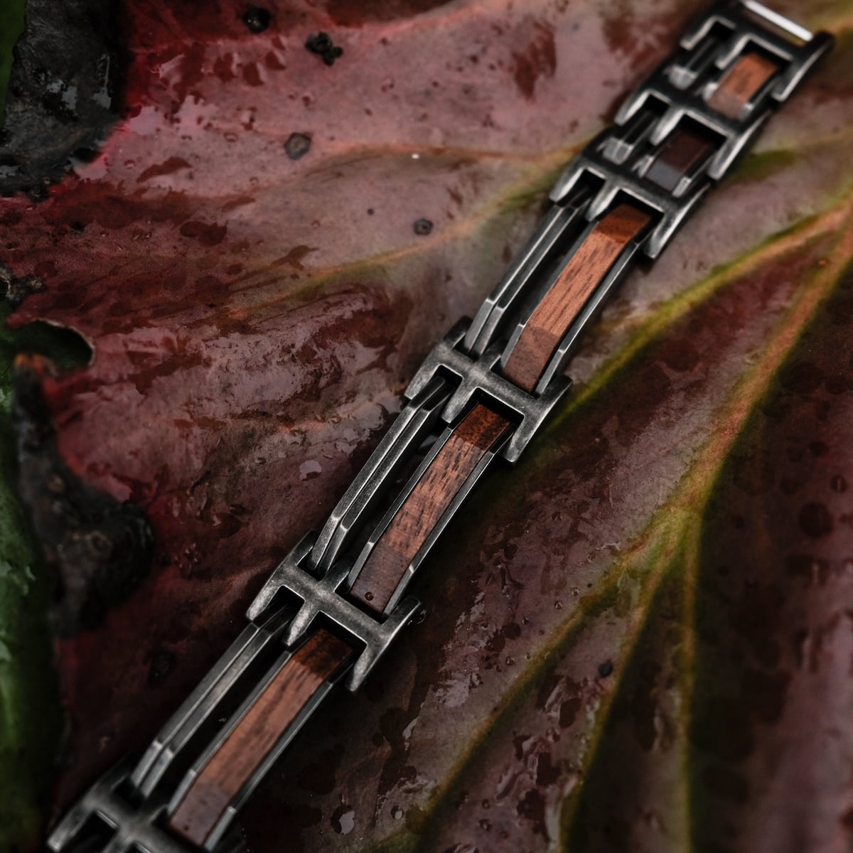 "Staccato" bracelet with walnut and antique silver accents on a leaf background.