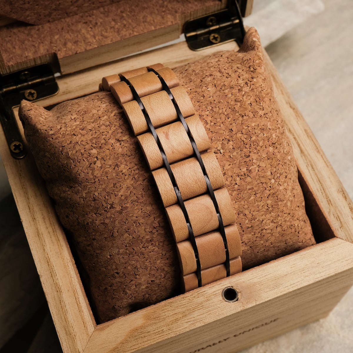 "Grandezza" watch with a maple and dark purple design, elegantly displayed on a cork cushion inside a wooden box.