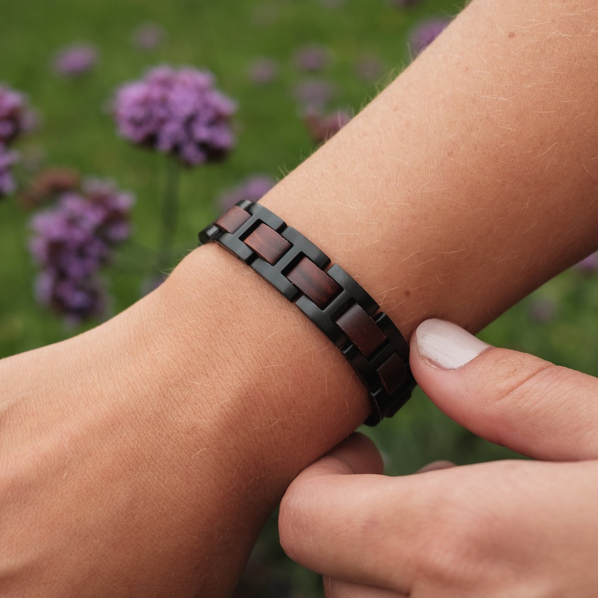 "Acoustic" bracelet featuring a Padauk and Black style, elegantly worn on a wrist against a floral background.