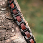 "Acoustic", a stylish watch with a bold Padauk and black color scheme, elegantly displayed on rough wood.