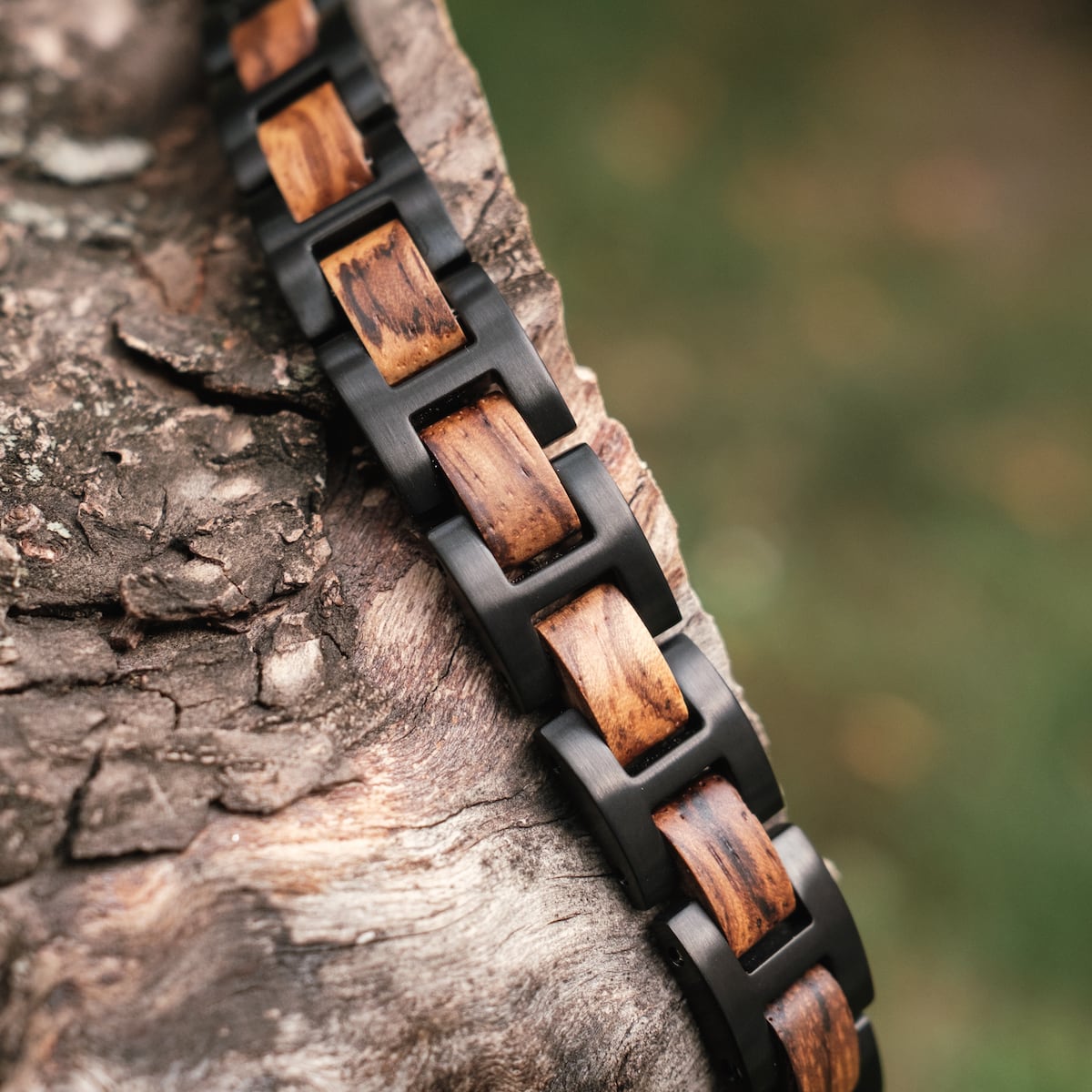 "Acoustic" bracelet featuring zebrawood and black accents, styled on textured bark for an earthy aesthetic.