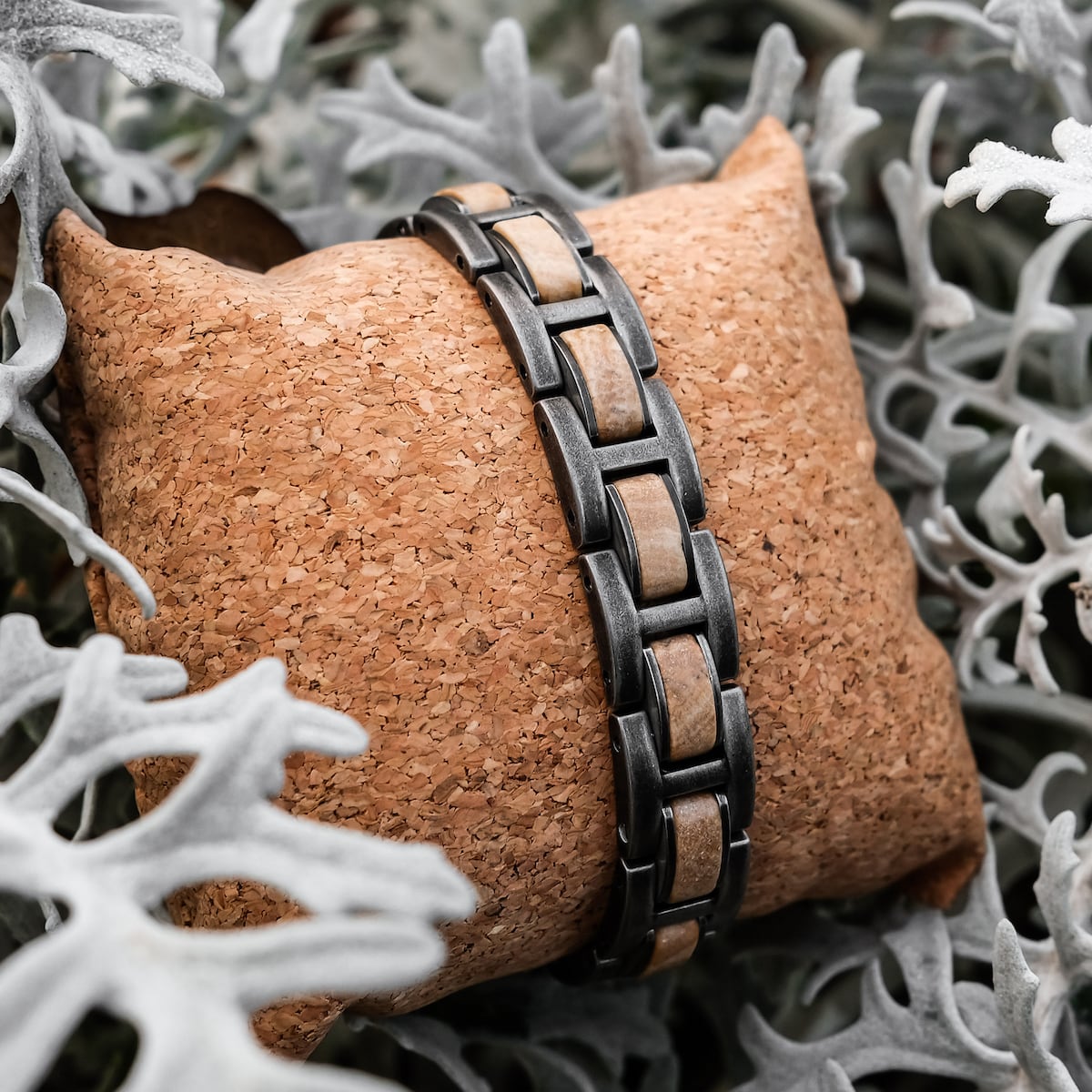 "Forte" bracelet featuring a marble and antique silver design amidst soft foliage.
