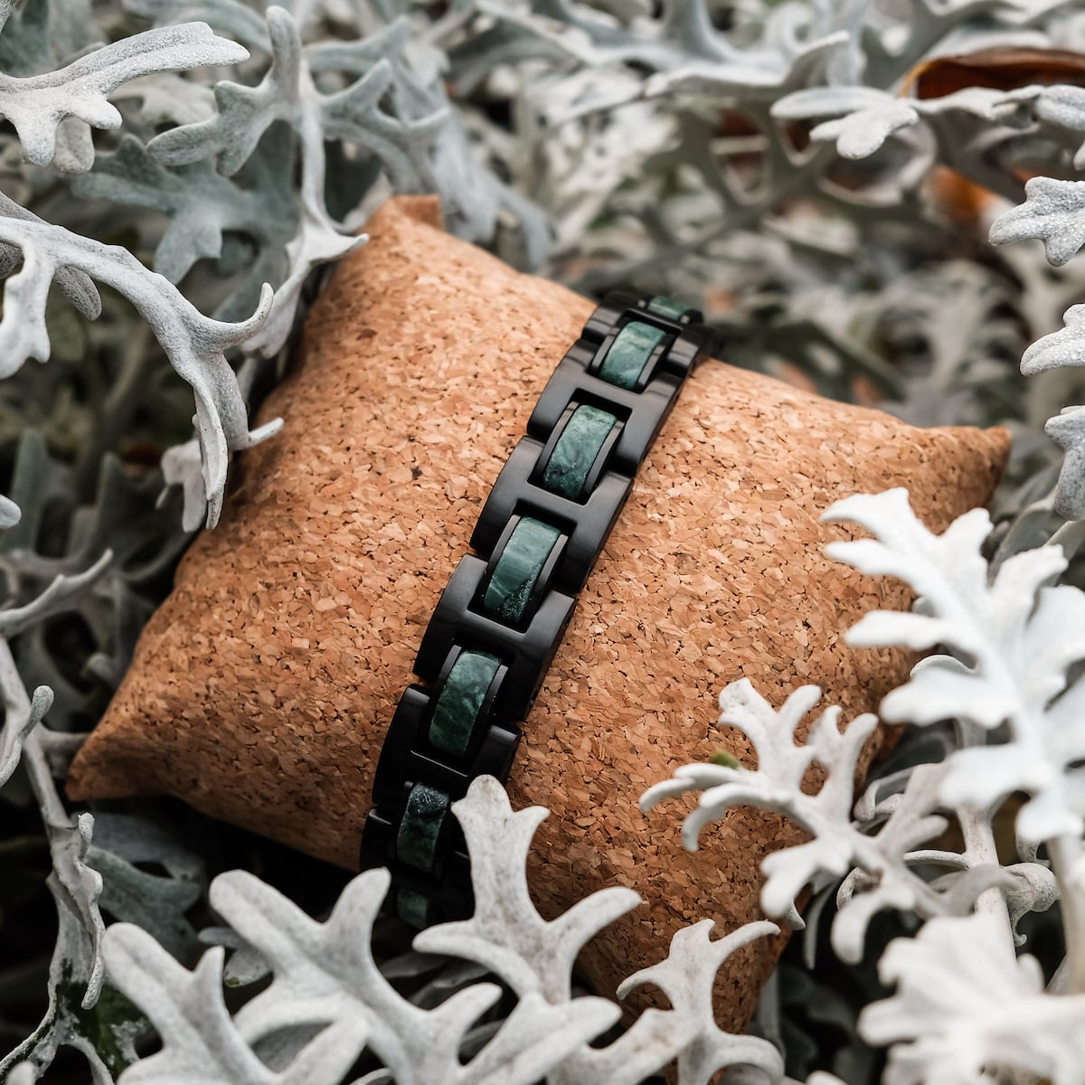 "Forte", a stylish black and marble bracelet, showcased amidst elegant foliage.