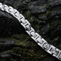 "Forte" bracelet in marble and silver with a sleek, modern design displayed on a rock surface.