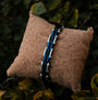 "Allegro" bracelet featuring a sleek maple and silver design on a textured cushion.