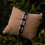 "Allegro", a stylish bracelet, featuring a walnut and silver combination on a cork cushion background.