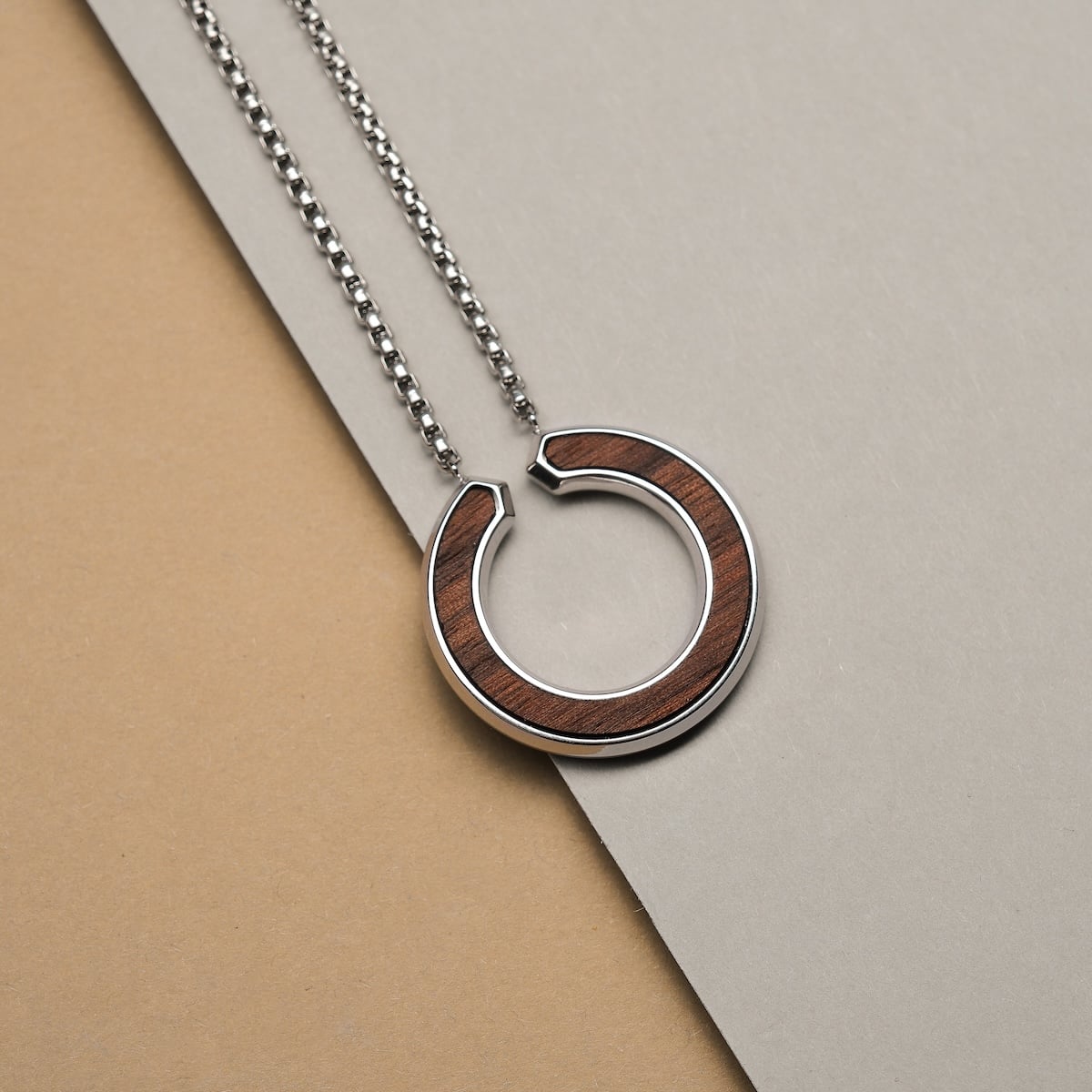 "Inseparable L" necklace featuring walnut and silver materials with a modern circular design.