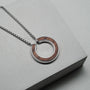 "Inseparable L" necklace featuring a walnut and silver circular pendant on a sleek chain.