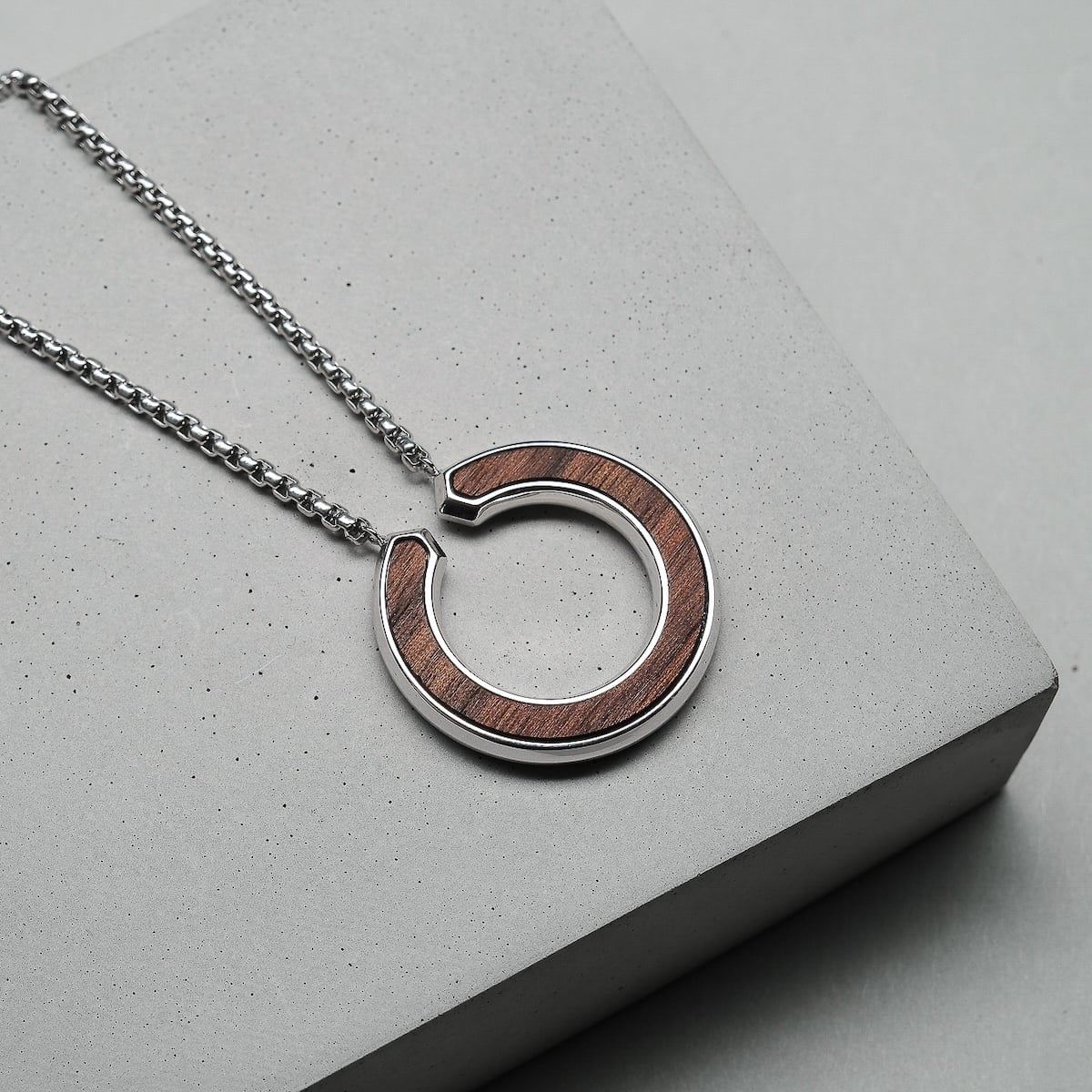 "Inseparable L" necklace featuring a walnut and silver circular pendant on a sleek chain.