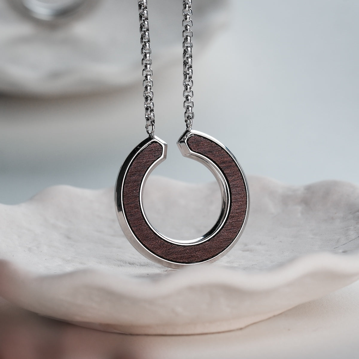 "Inseparable S" necklace, featuring a walnut and silver finish, with an elegant circular design.