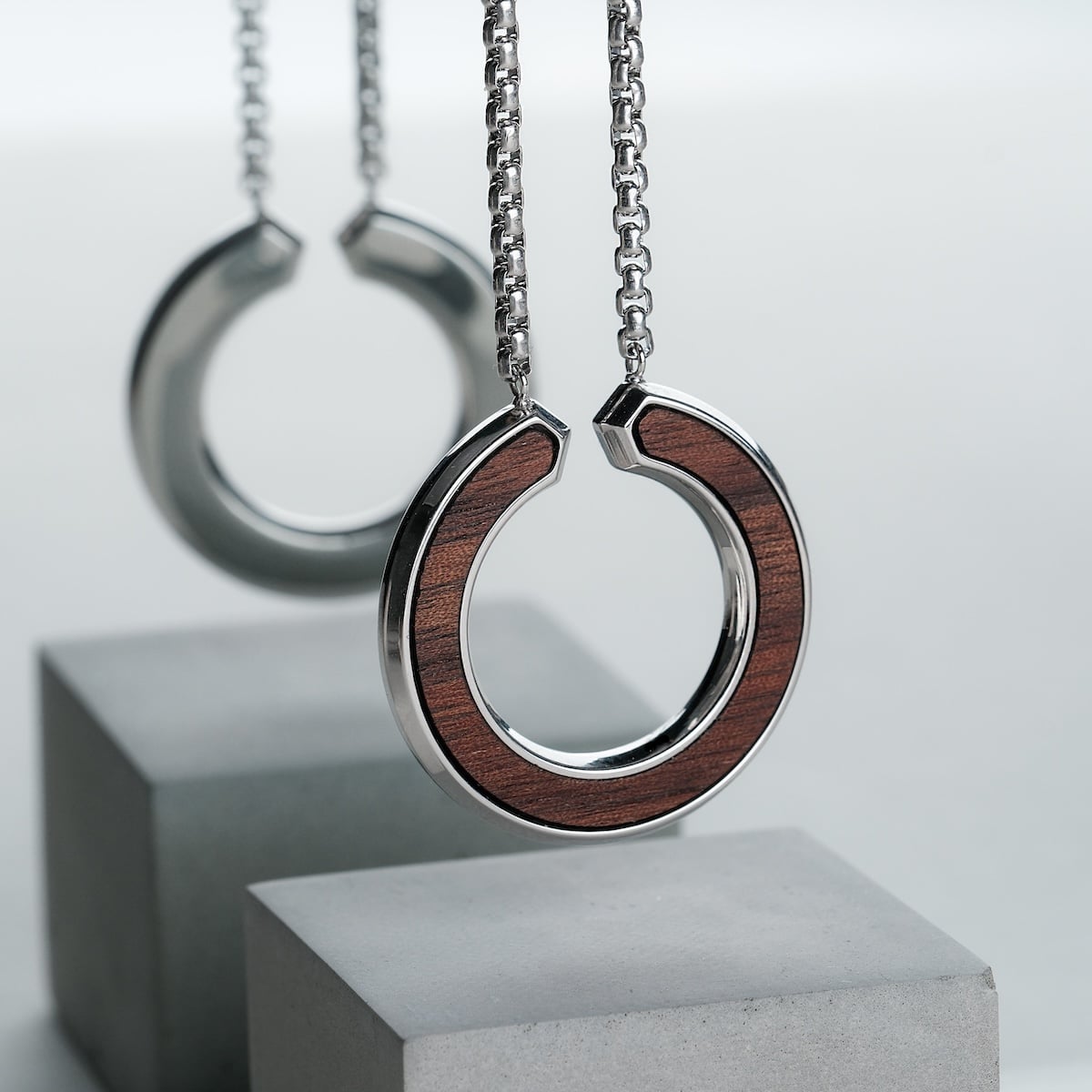 "Inseparable L" necklace with a walnut and silver finish, featuring a modern circular design.