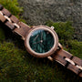 Euterpe watch with a Walnut band and marble face on a mossy background.