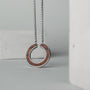 "Inseparable L", a walnut and silver necklace, featuring a sleek circular pendant design.