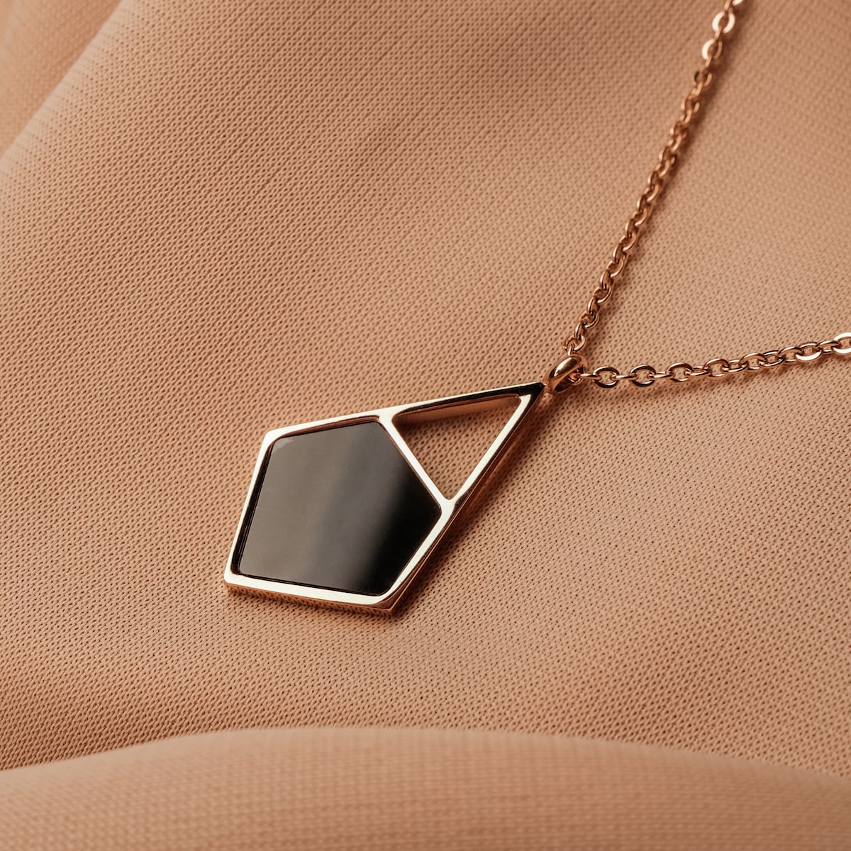 "Mandala Necklace necklace featuring a geometric pendant with a marble and rose gold design on a soft fabric background."