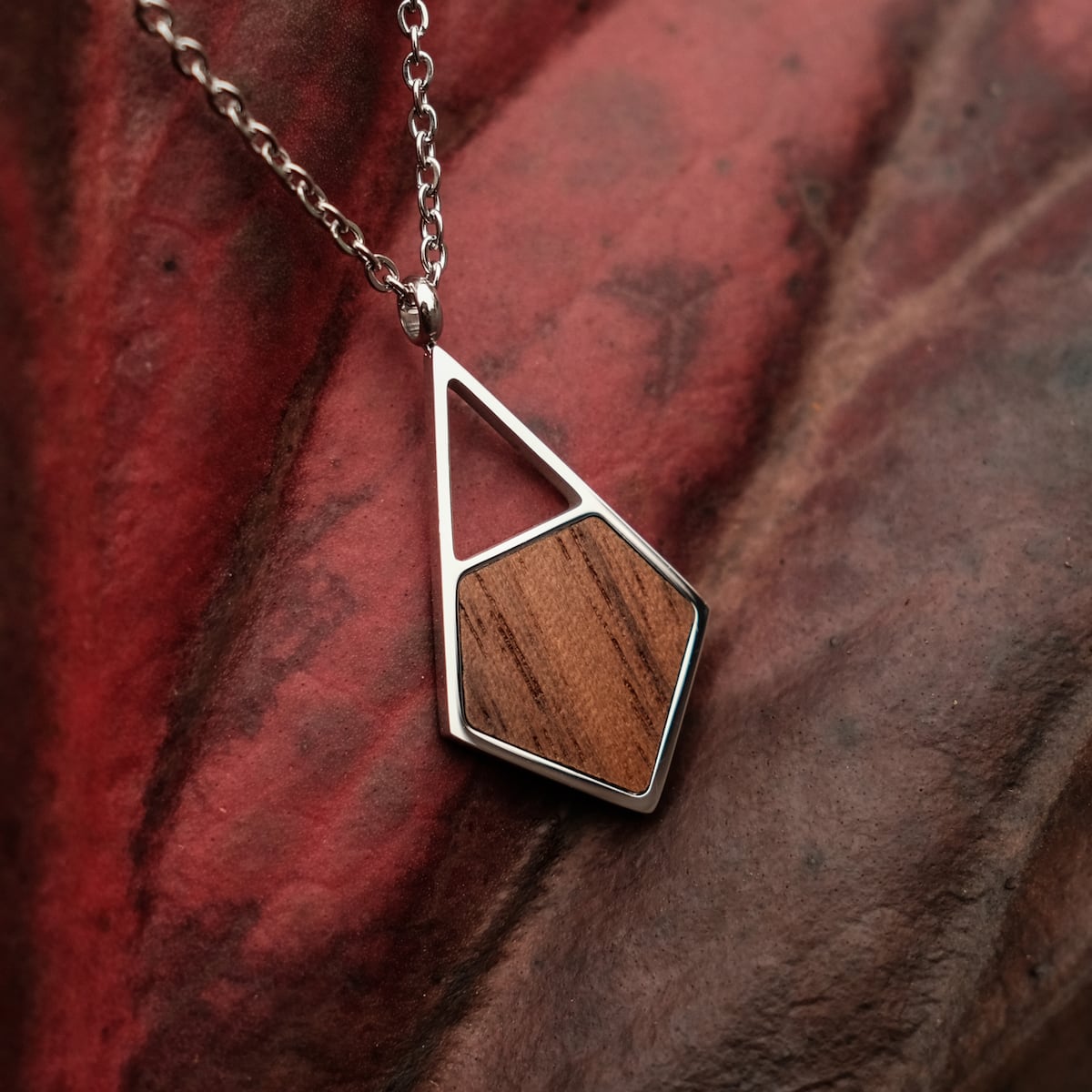 "Mandala Necklace": a unique geometric necklace featuring walnut and silver, set against a rich, textured backdrop.