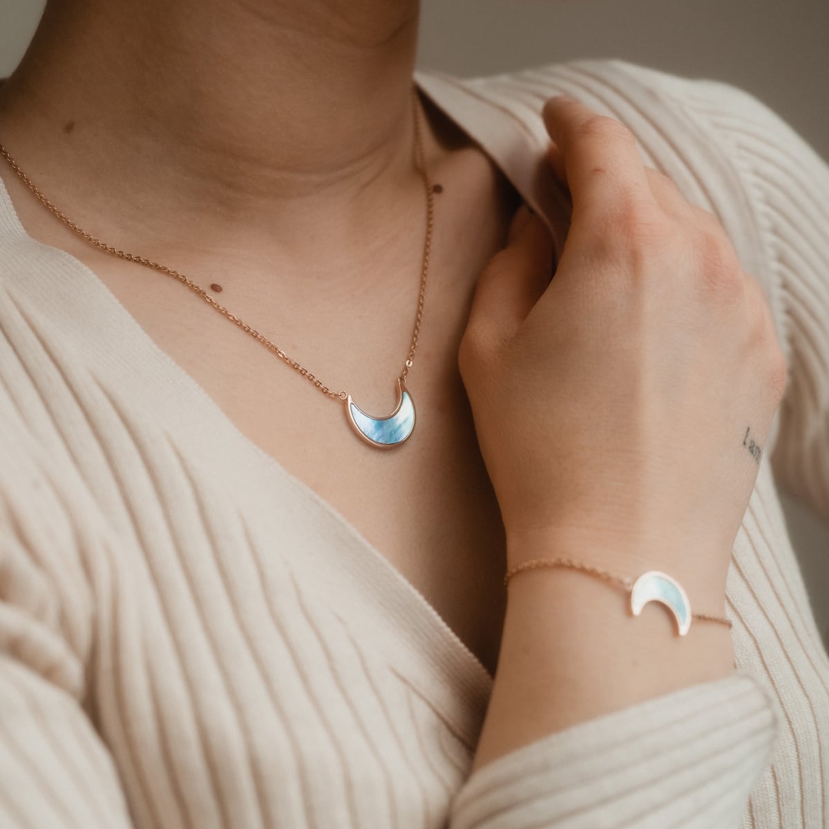 "Hue Necklace" necklace, featuring a crescent design with blue nacre and rose gold accents, worn elegantly.